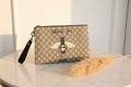Elegant front view of Gucci Blind for Love bee GG Supreme pouch on marble surface